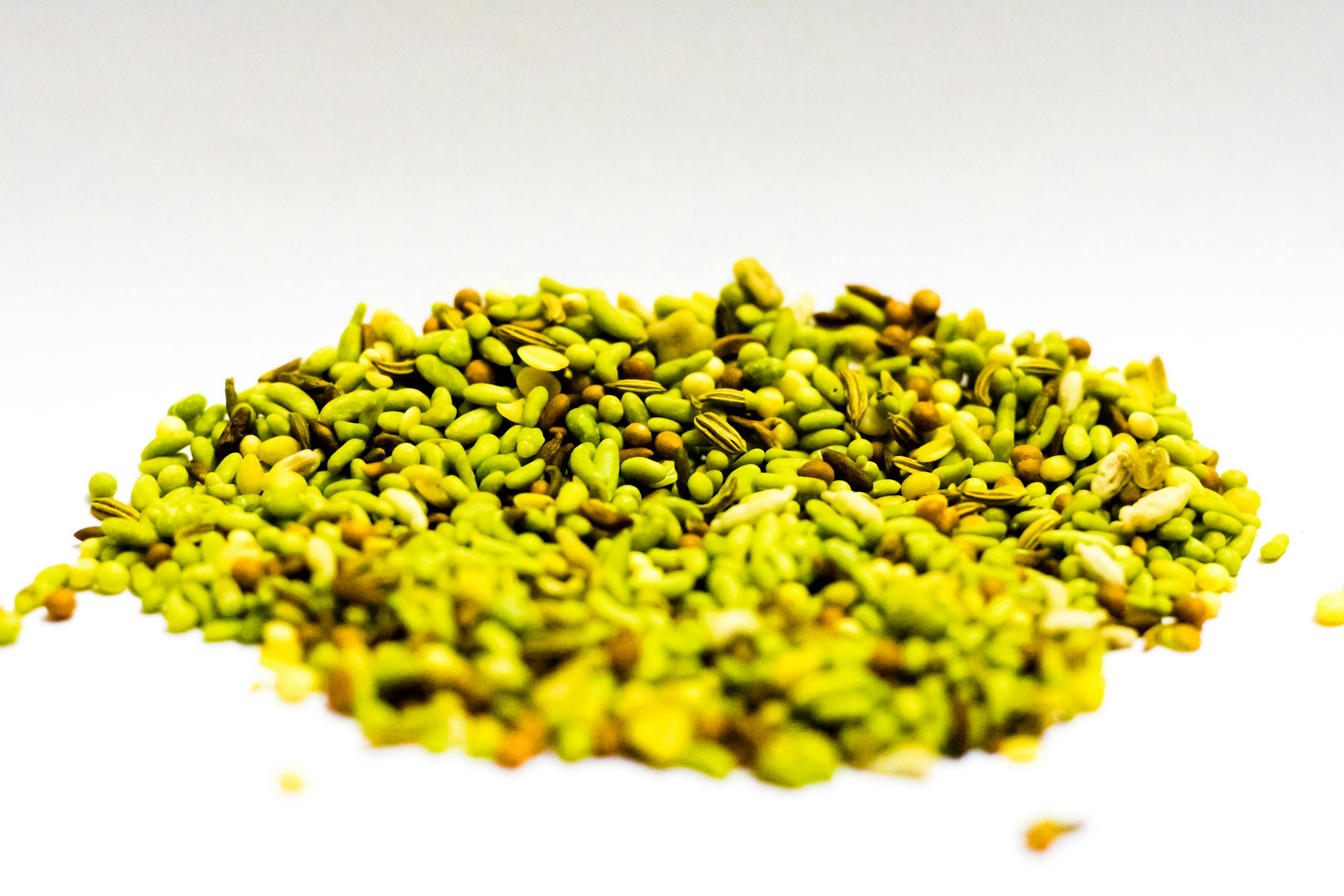Un tas de graines de fenouil et d'épices colorées sur un fond lumineux.